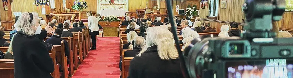 Family and friends gathered in a chapel while our camera live streams a funeral service